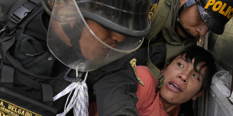 Un manifestante e alcuni poliziotti durante la manifestazione di giovedì a Lima, la capitale del Perù (AP Photo/Martin Mejia)
