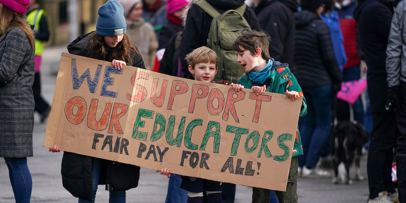 Tre bambini con un cartello che dice «noi sosteniamo i nostri educatori» a Newcastle, in Inghilterra (Photo by Ian Forsyth/Getty Images)