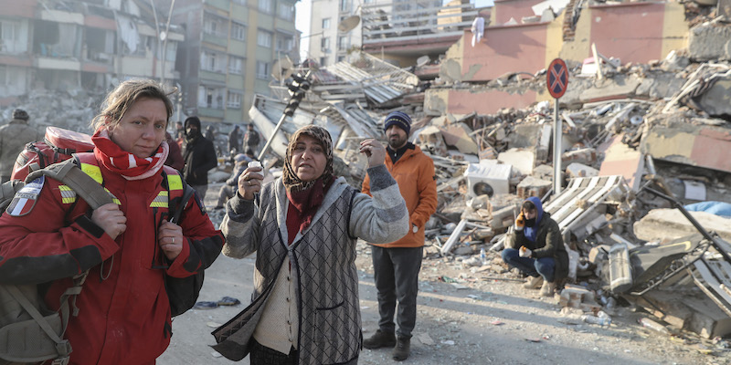 Una soccorritrice e una donna che grida tra gli edifici distrutti di Hatay, in Turchia