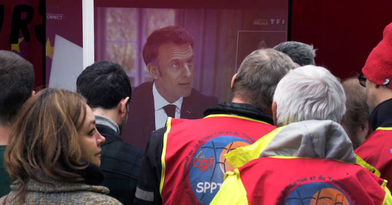 Alcune persone in sciopero guardano l'intervista di Macron a un presidio sindacale (AP Photo/Christophe Ena)