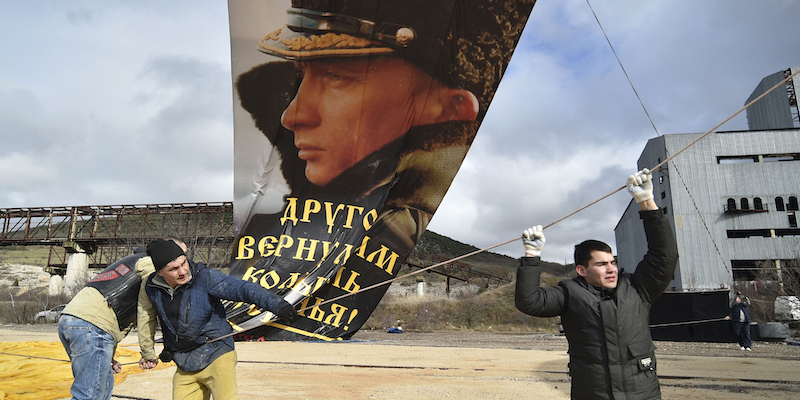 Tre sostenitori issano una gigantografia del presidente russo Vladimir Putin per le celebrazioni dell'anniversario dell'annessione della Crimea nel 2014. Sebastopoli, Crimea, 18 marzo 2021. (AP Photo)