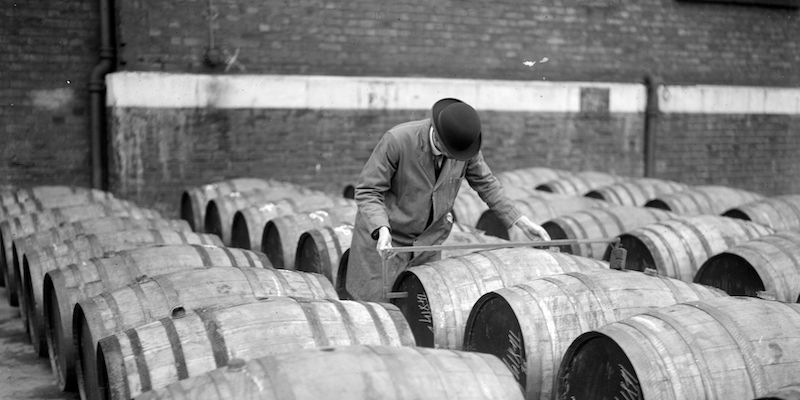 Un ufficiale del porto di Londra nel 1929, intento a misurare la dimensione di barili appena sbarcati (Photo by Fox Photos/Getty Images)