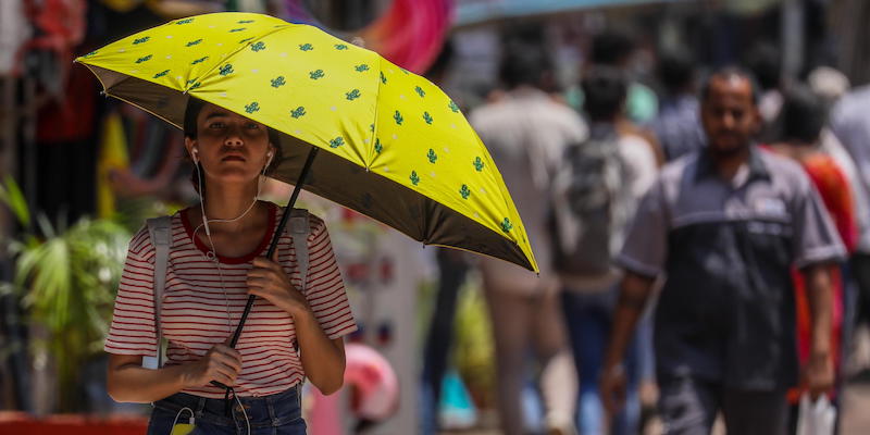 Una donna si ripara dal caldo con un ombrello a Mumbai, lunedì 17 aprile
