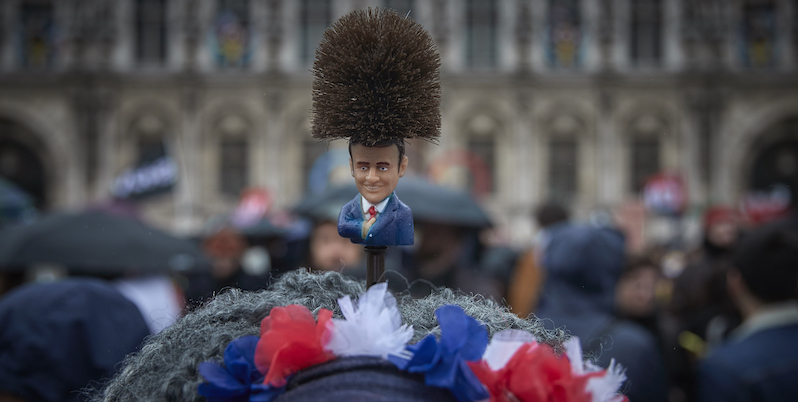 Un piccolo Macron sulla testa di una donna che protesta contro la riforma delle pensioni, Parigi, 14 aprile 2023 (Kiran Ridley/Getty Images)