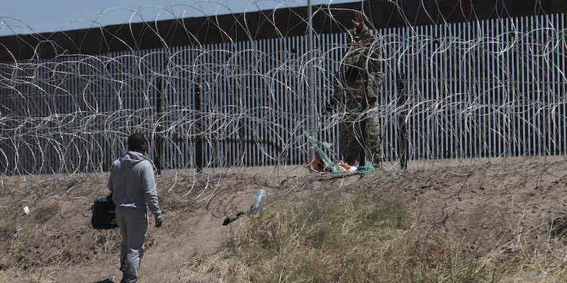 Una persona migrante parla con un membro delle forze dell'ordine statunitense al confine tra Stati Uniti e Messico, il 30 aprile 2023 (AP Photo/Christian Chávez)