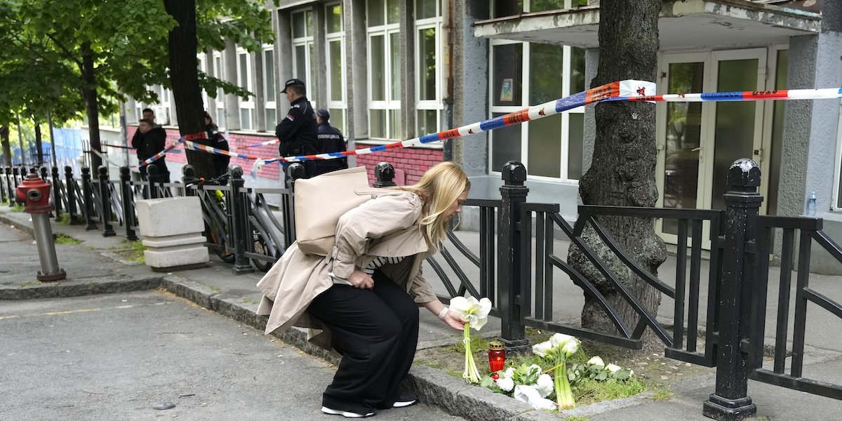 Una donna posa un mazzo di fiori fuori dalla scuola dove è stato compiuto l'attacco (AP Photo/Darko Vojinovic)
