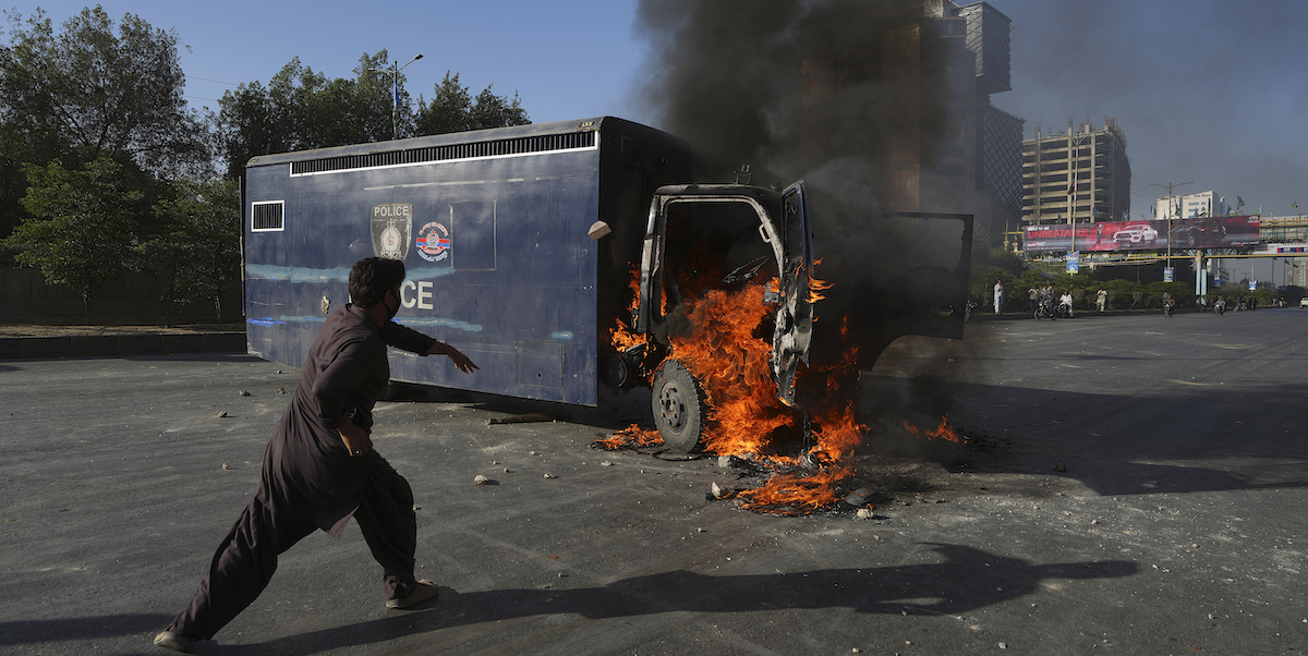 Una camionetta della polizia incendiata durante una protesta a Karachi (AP Photo/Fareed Khan)