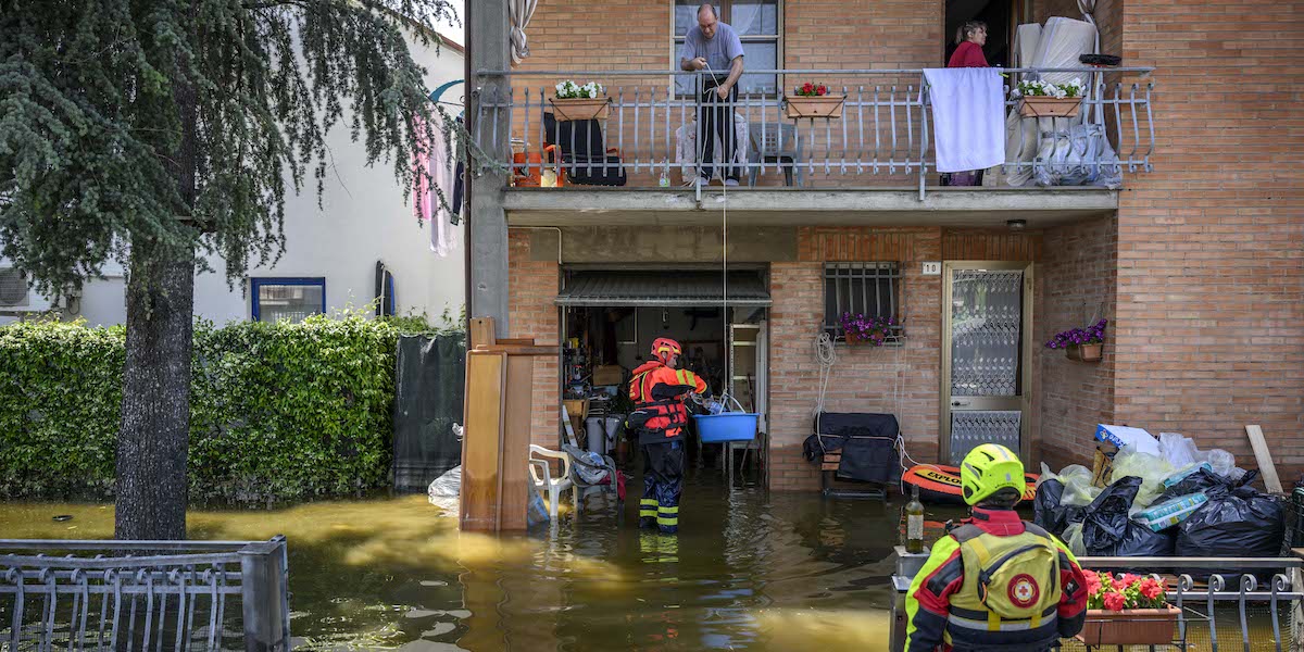Un vigile del fuoco e un operatore della Croce Rossa assistono una famiglia che vive in una casa allagata a Conselice, in provincia di Ravenna