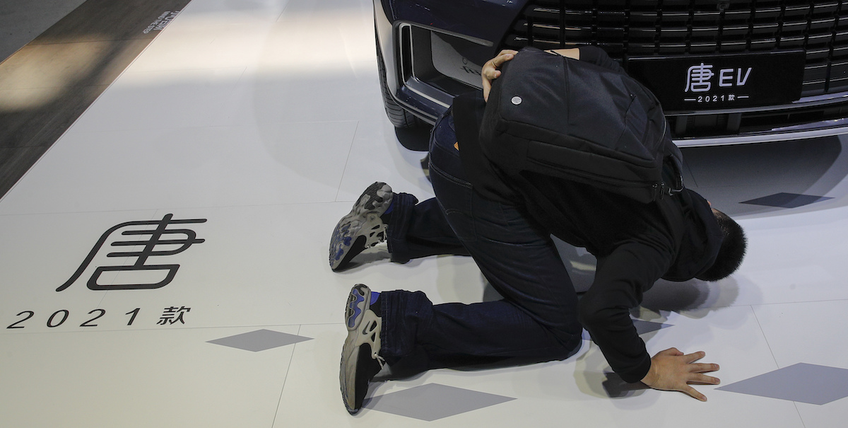 Un curioso ispeziona un'auto esposta alla fiera Auto China del 2020 a Pechino. (AP Photo/Andy Wong)