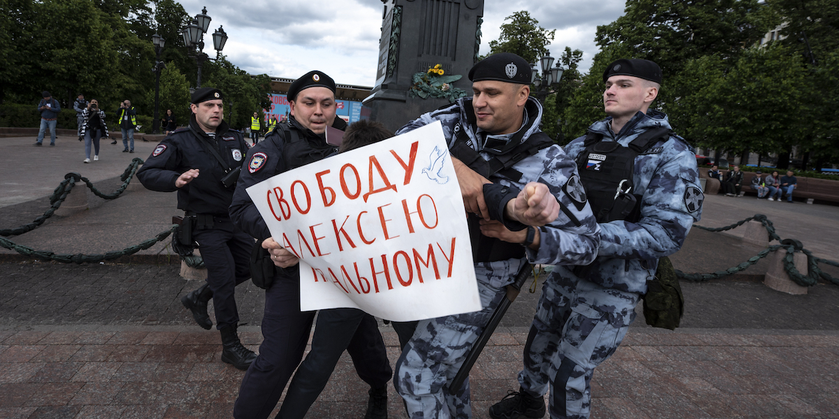 Un uomo con un cartello con la scritta “Libertà per Alexei Navalny” arrestato da alcuni poliziotti a Mosca (AP Photo)
