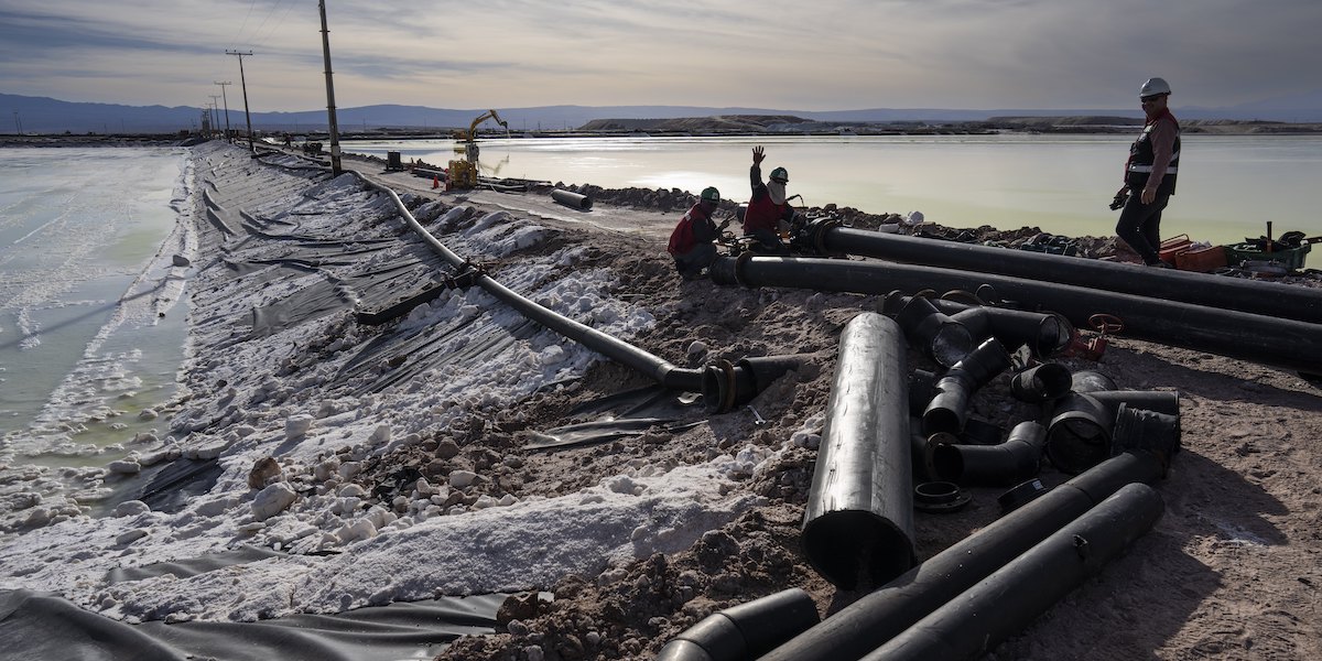 Operai al lavoro accanto a una delle vasche per la produzione di litio nel deserto di Atacama, in Cile, il 18 aprile 2023 (AP Photo/Rodrigo Abd, LaPresse)