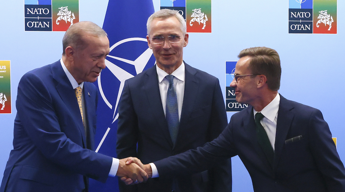 Il presidente turco Recep Tayyip Erdogan stringe la mano al primo ministro svedese Ulf Kristersson, con al centro il segretario generale della NATO Jens Stoltenberg (Yves Herman, Pool Photo via AP)
