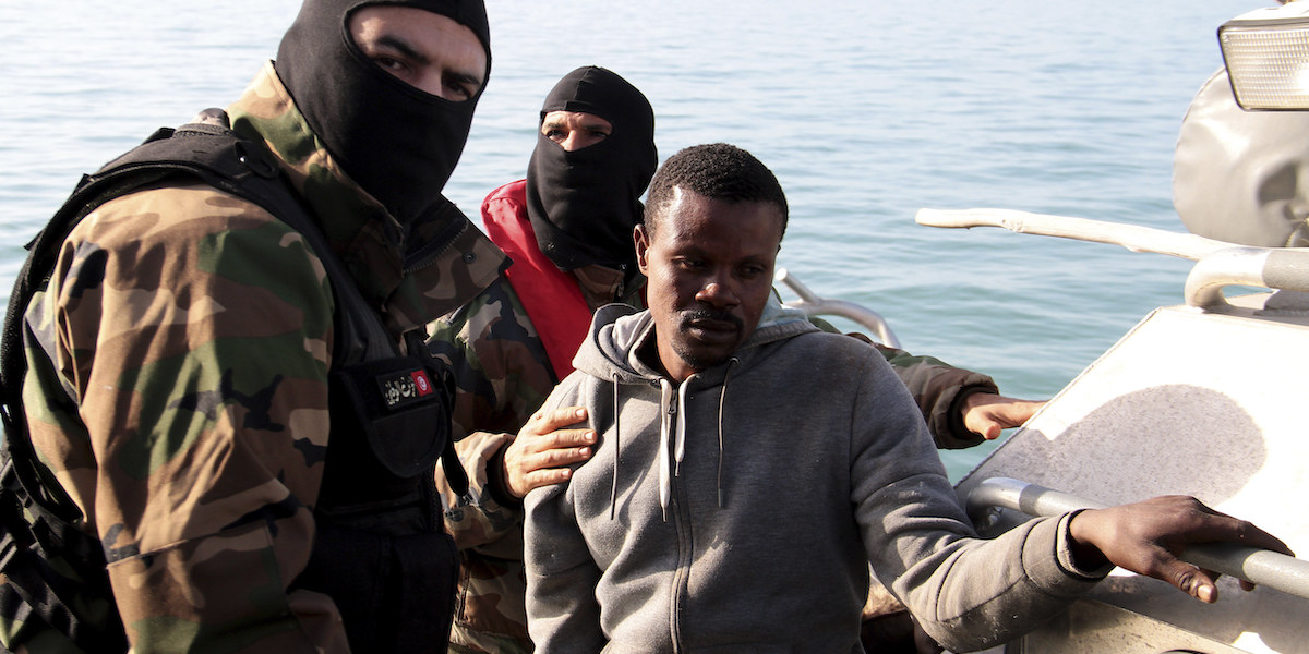 Un agente della Guardia nazionale marittima tunisina ferma un'imbarcazione di migranti subsahariani diretta in Italia, 27 aprile 2023 (AP Photo)