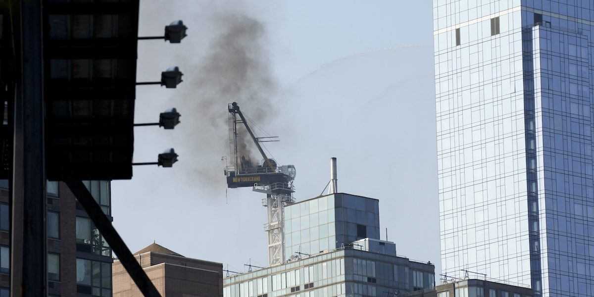 La gru incendiata e parzialmente crollata nel centro di New York, il 26 luglio 2023 (AP Photo/Seth Wenig, LaPresse)