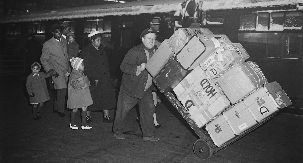 Un facchino inglese trasporta i bagagli di una famiglia che sta lasciando il Regno Unito per tornare nei Caraibi. Stazione di Waterloo, Londra, 1962 (Edward Miller/Keystone/Hulton Archive/Getty Images)