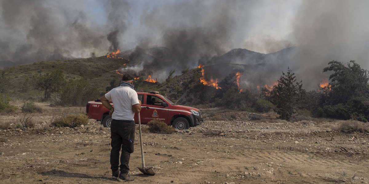 Un uomo osserva un incendio nella località di Vati, sull'isola di Rodi, lo scorso 25 luglio (AP Photo/ Petros Giannakouris)