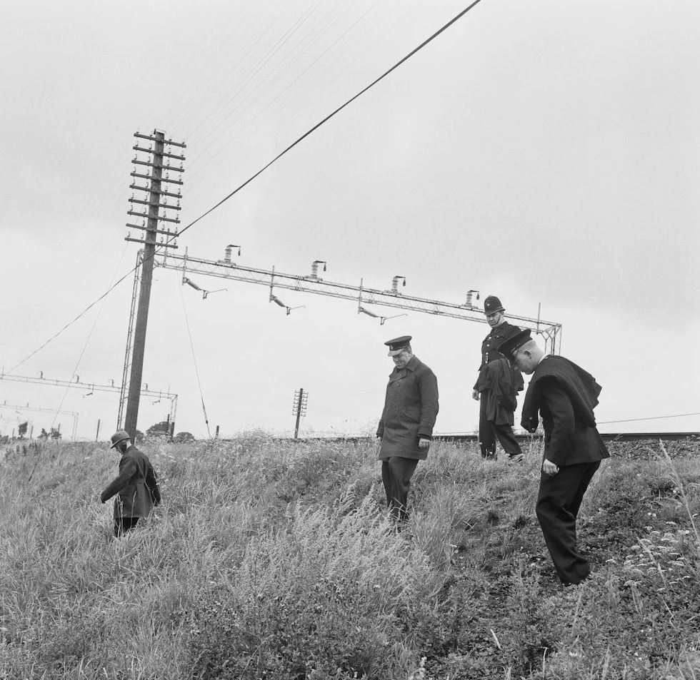 Agenti di polizia cercano indizi vicino ai binari della ferrovia l'8 agosto del 1963
