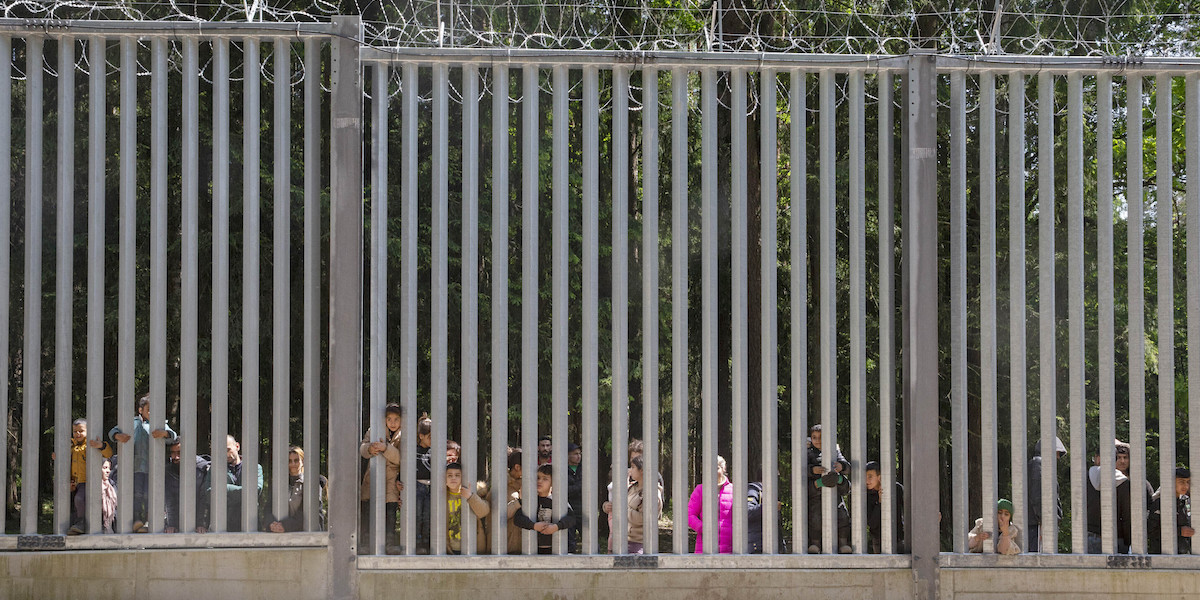 Un gruppo di migranti dietro il muro che il governo polacco ha fatto costruire al confine con la Bielorussia (AP Photo/Agnieszka Sadowska, File)