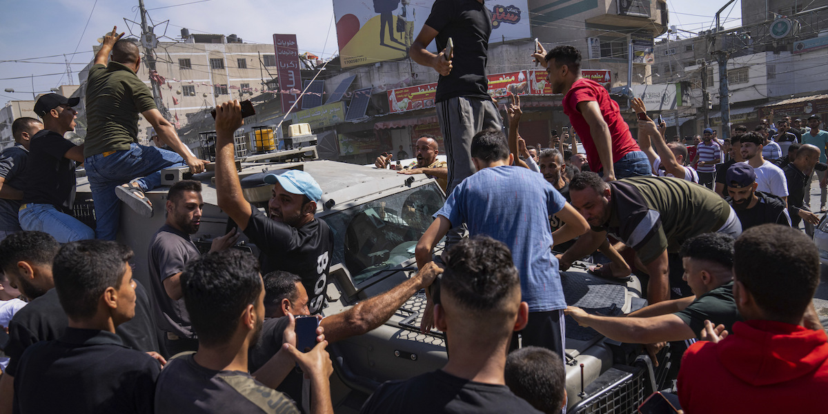 Uomini palestinesi esultano su un veicolo israeliano sequestrato e portato nella Striscia di Gaza (AP Photo/Fatima Shbair)