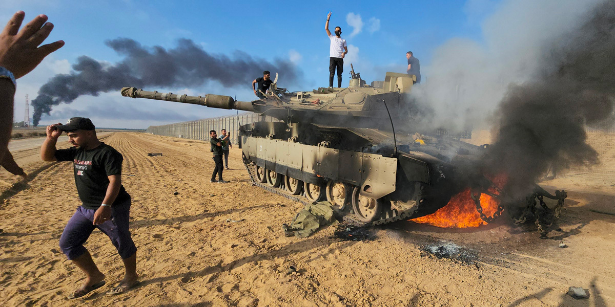 Miliziani palestinesi festeggiano vicino a un carro armato, nella Striscia di Gaza (AP Photo/Hassan Eslaiah) 