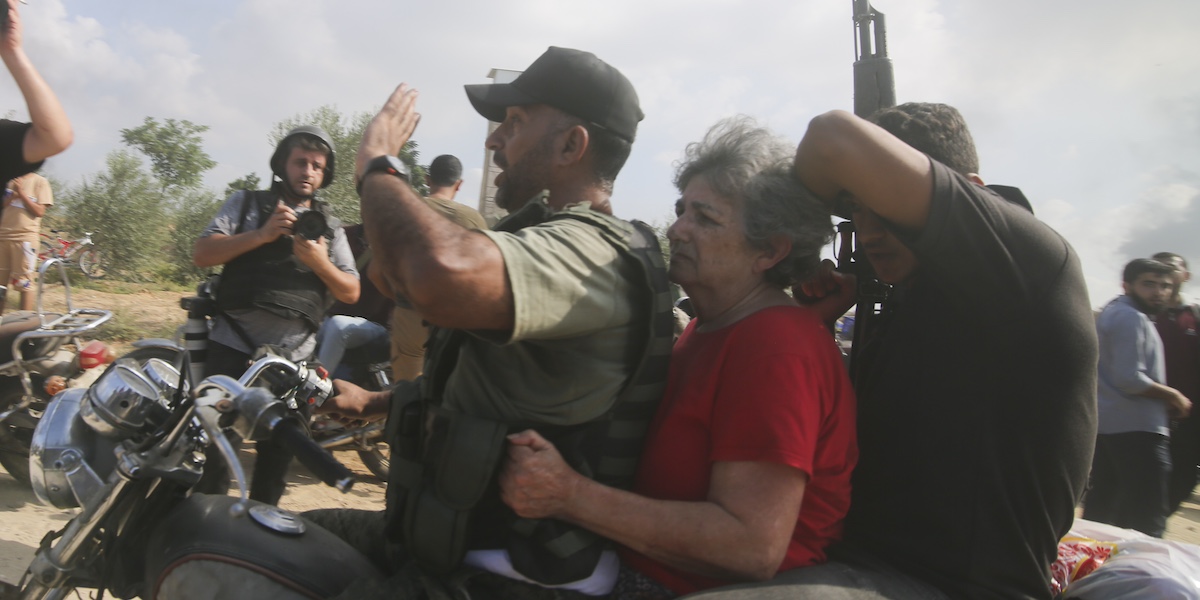 Miliziani palestinesi portano una donna israeliana come ostaggio all’interno della Striscia di Gaza (AP Photo/Hatem Ali)