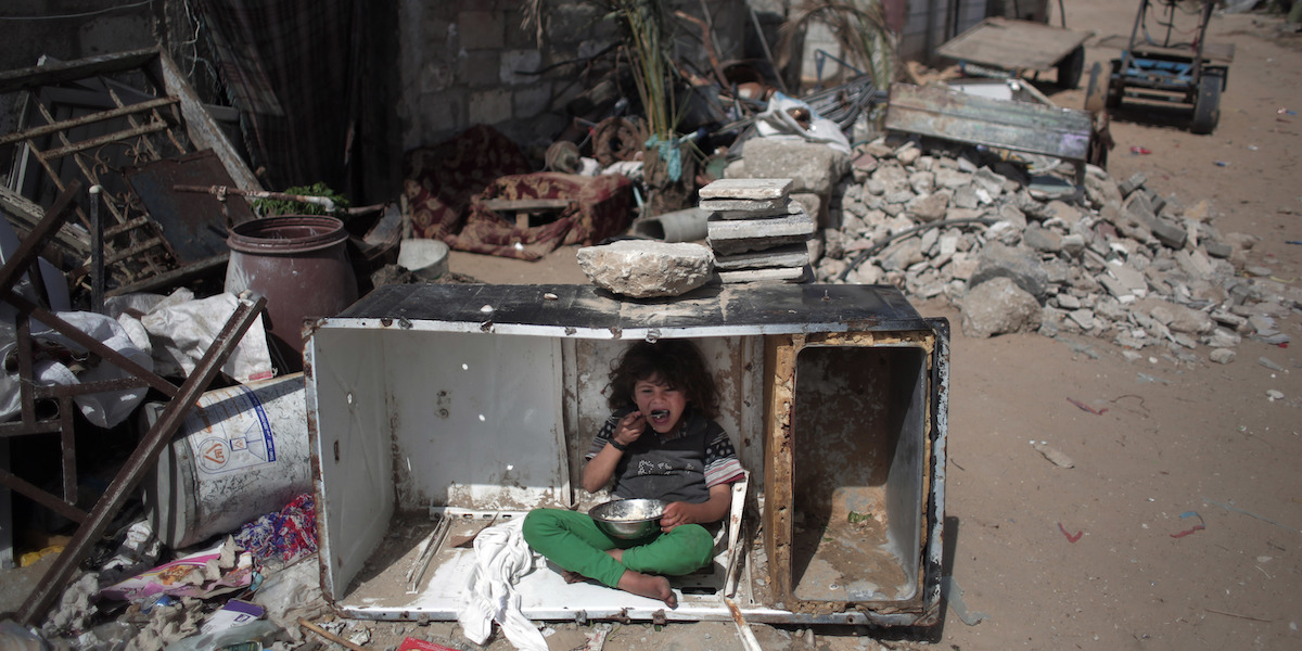 Una bambina palestinese mangia dentro i rottami di un frigorifero nel campo profughi di Khan Younis (AP Photo/ Khalil Hamra)