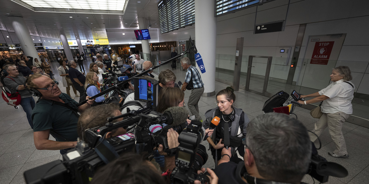 Una ragazza appena atterrata all'aeroporto di Monaco da Tel Aviv viene intervistata dai giornalisti (Lukas Barth/dpa via AP)