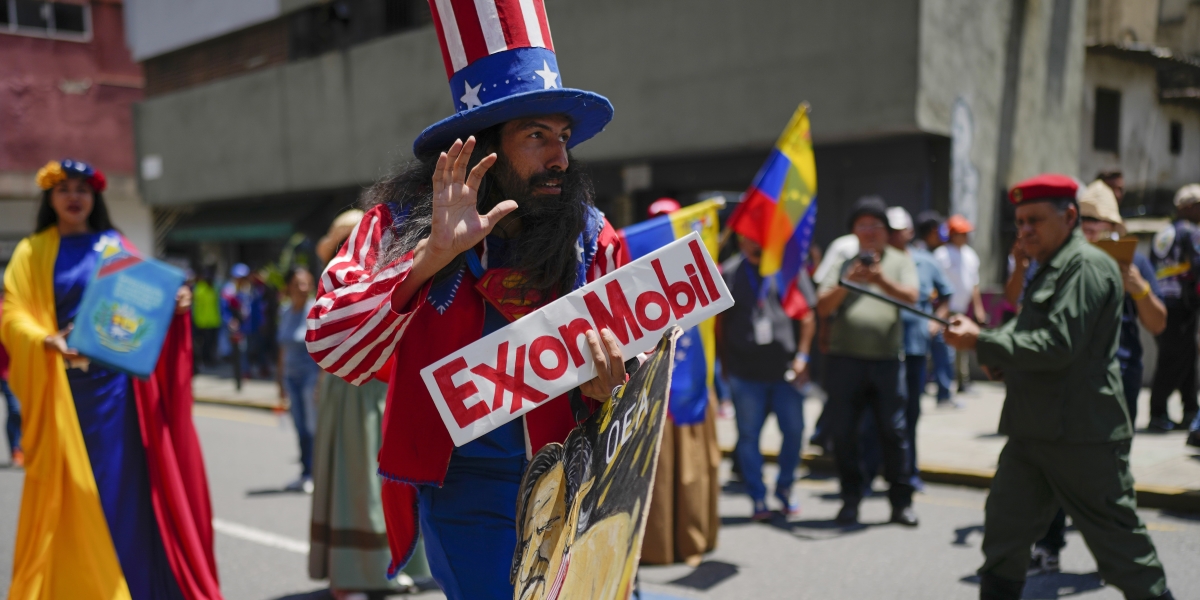 Un manifestante vestito da Zio Sam, caricatura degli Stati Uniti, con un cartello che porta il nome di un'importante compagnia petrolifera statunitense, a una manifestazione filogovernativa in Venezuela (AP Photo/Ariana Cubillos)