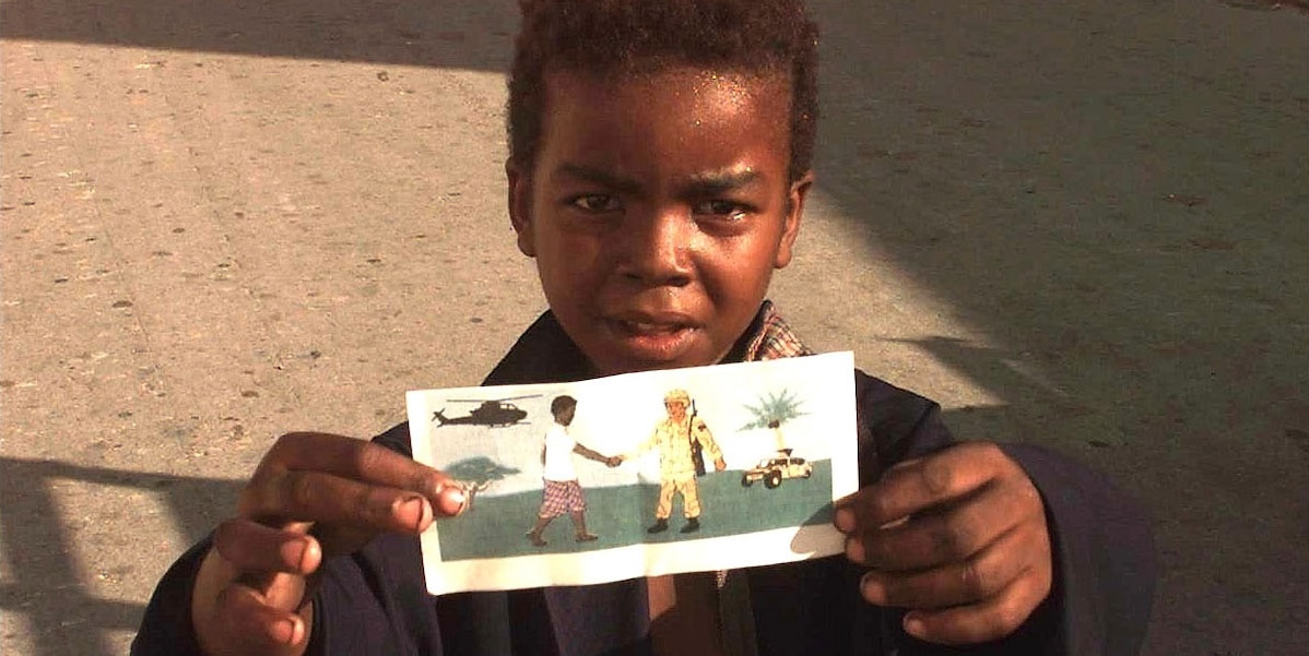 Un bambino somalo mostra un volantino durante l'operazione Restore Hope del 1993 (Wikicommons)