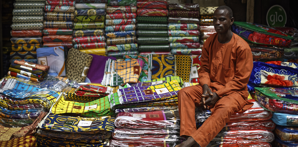 Un venditore di tessuti stampati in wax prodotti in Cina nel mercato di Kano in Nigeria (AP Photo/Ben Curtis)