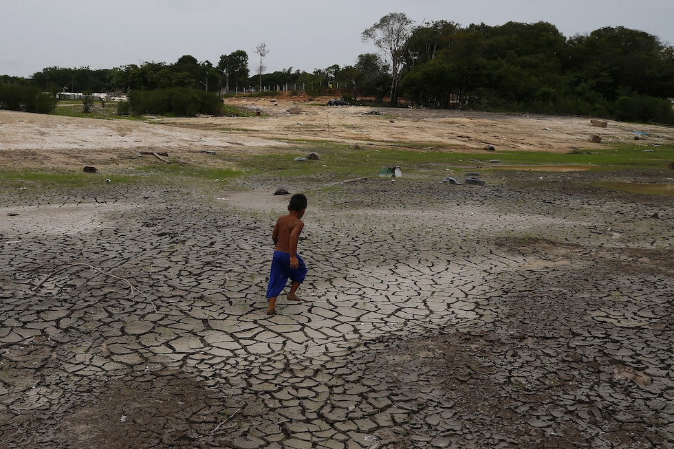 Un bambino cammina su una parte del letto del Rio Negro in secca vicino a Manaus
