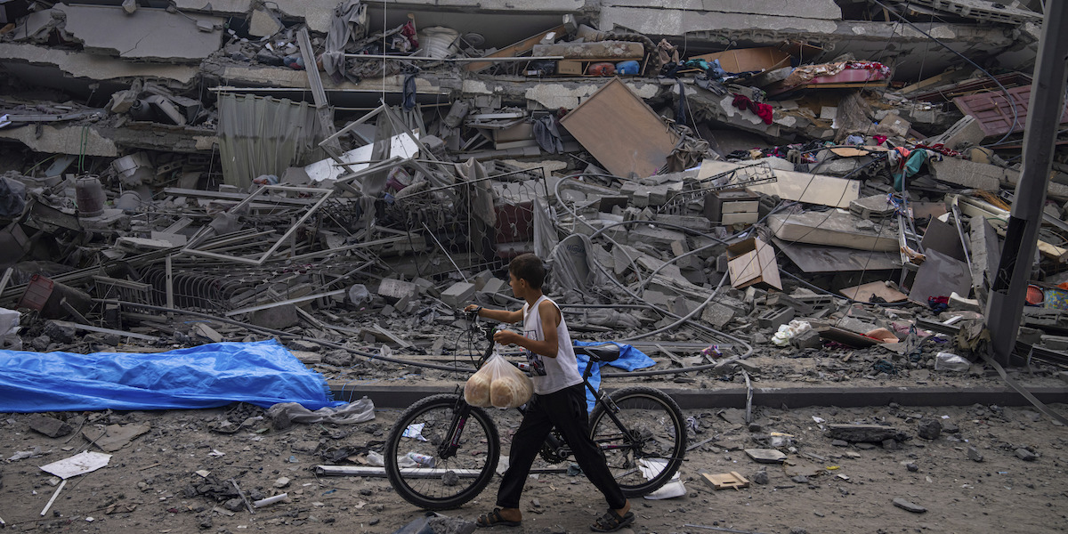  Un bambino palestinese cammina davanti ad alcuni edifici distrutti nella città di Gaza (AP Photo/Fatima Shbair, File)