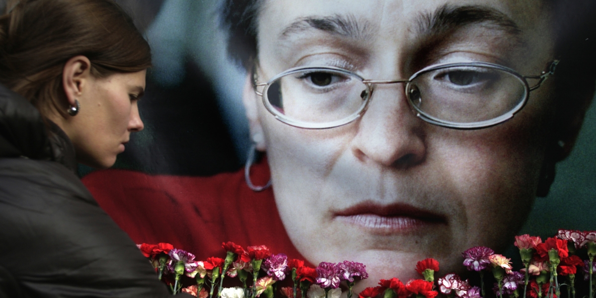 Una donna depone dei fiori davanti a un ritratto di Anna Politkovskaya (AP Photo/Pavel Golovkin, File)