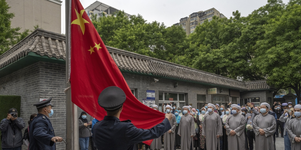 Una bandiera cinese viene issata prima di una celebrazione religiosa islamica davanti a una moschea di Pechino (Kevin Frayer/Getty Images)