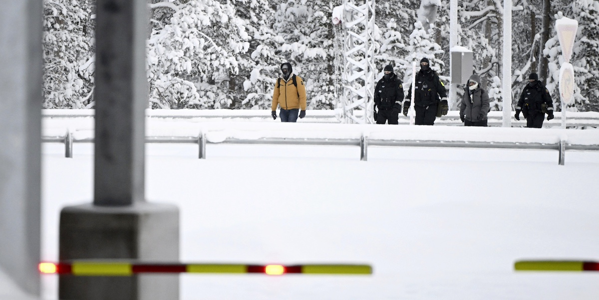 Guardie di frontiera finlandesi scortano due migranti al varco di confine di Raja-Jooseppi lunedì (Emmi Korhonen/Lehtikuva via AP)