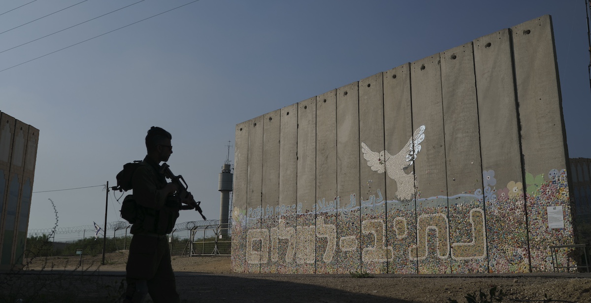 Un soldato israeliano vicino al muro di un kibbutz attaccato da Hamas il 7 ottobre (AP Photo/Leo Correa)