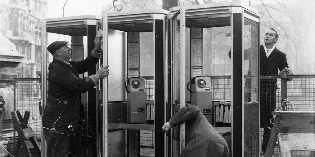 Operai puliscono telefoni pubblici a Londra nel 1962 dopo averli installati (foto Getty/Hulton Archive)