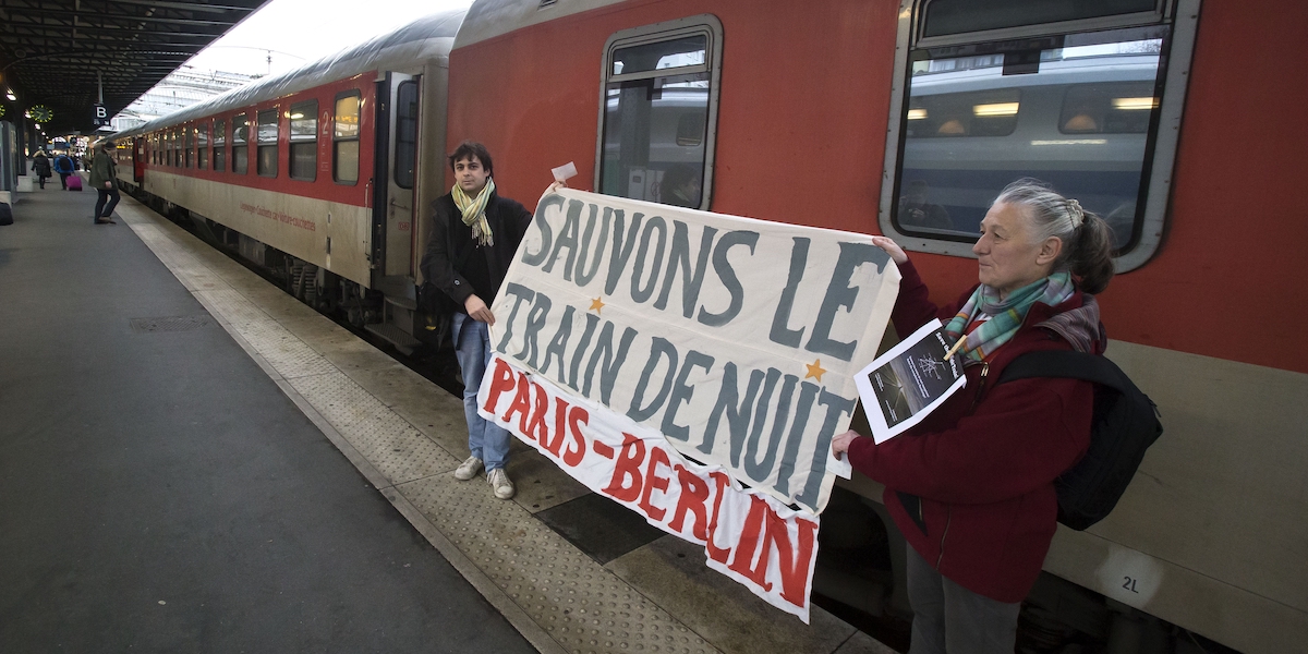Due attivisti francesi mostrano uno striscione all'arrivo del treno da Berlino alla stazione ferroviaria Gare de l'Est di Parigi. (AP/Michel Euler)