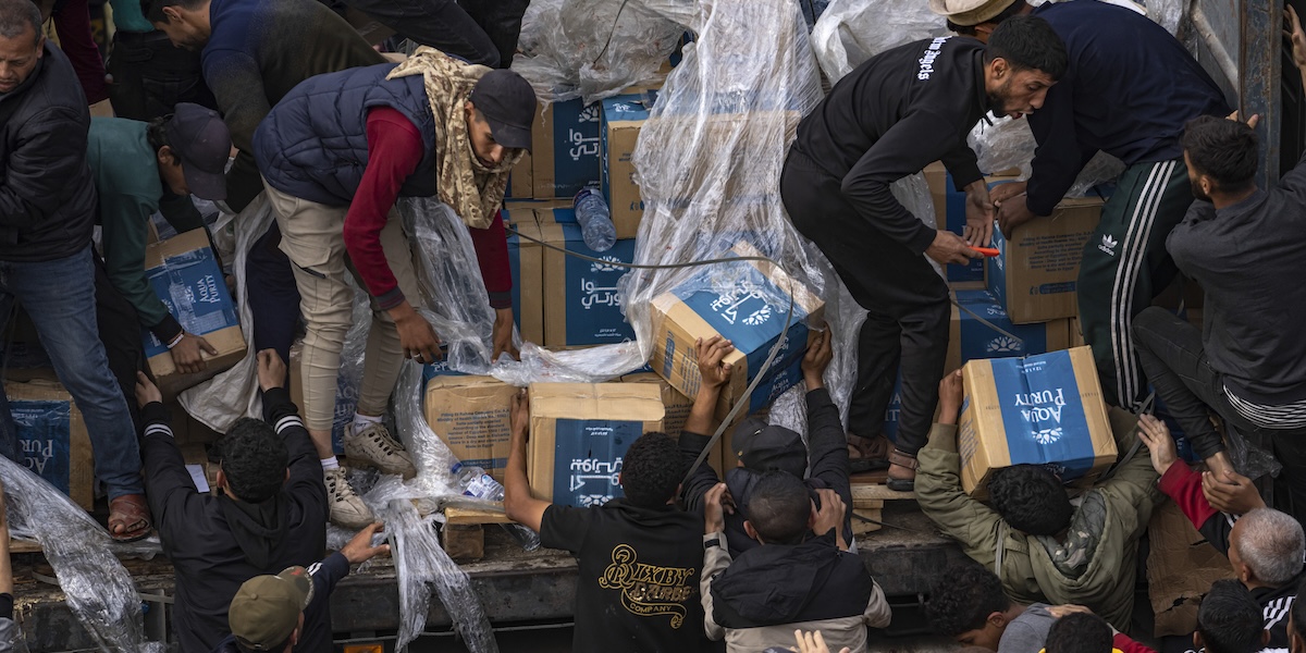 Persone palestinesi scaricano scatoloni di aiuti umanitari da un camion a Rafah, domenica 17 dicembre