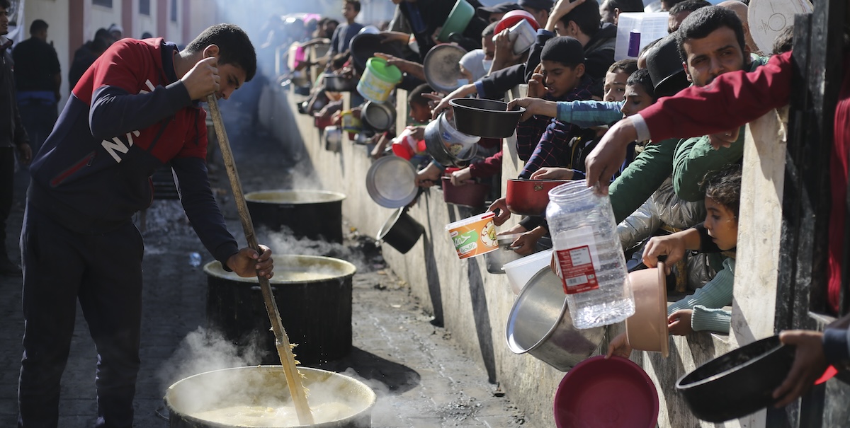 Persone palestinesi sfollate nella città di Rafah in fila per ricevere una razione di cibo. (AP Photo/Hatem Ali)