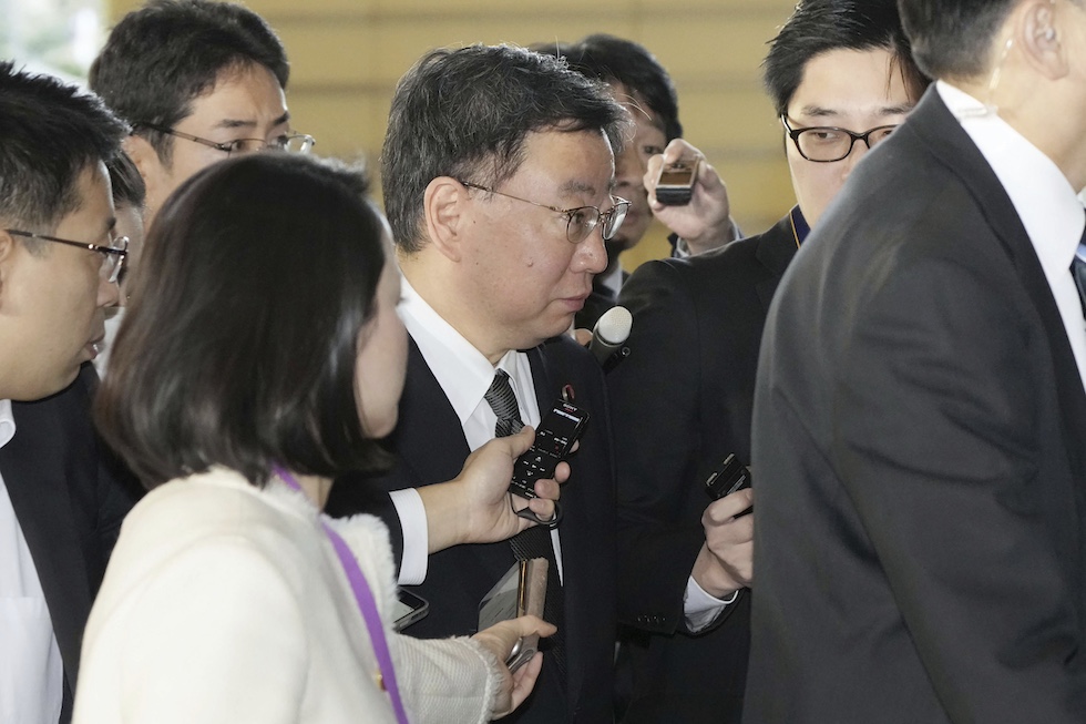 L'ex segretario di gabinetto Hirokazu Matsuno circondato da giornalisti pochi giorni prima delle sue dimissioni (Kyodo News via AP)
