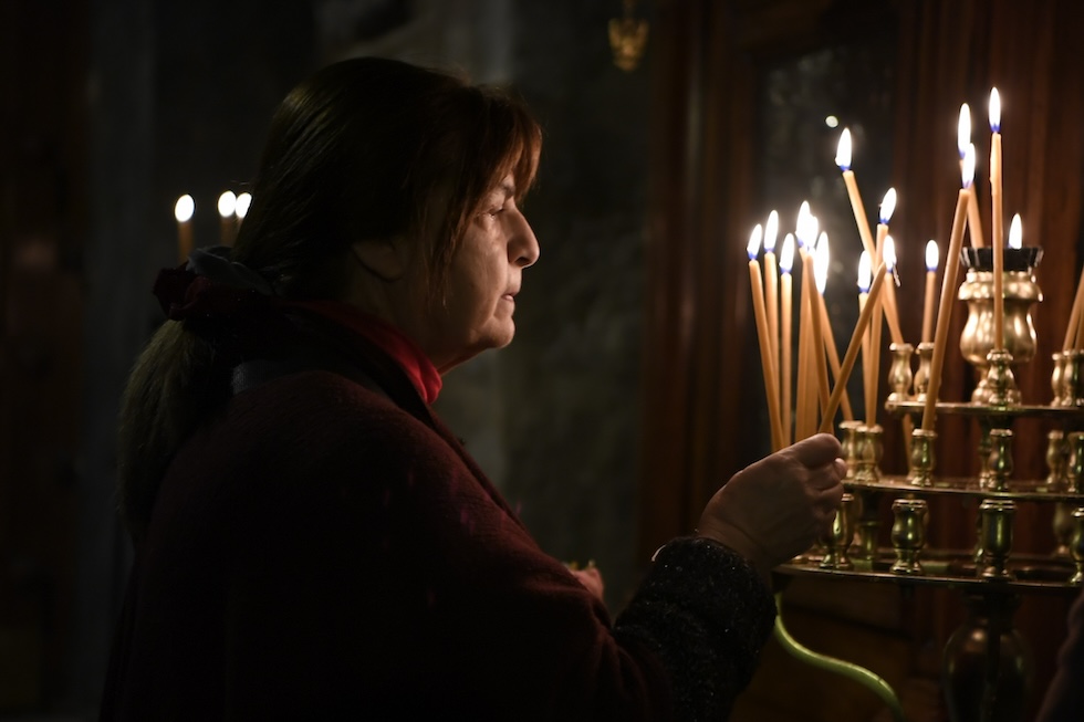 Una donna accende una candela nella chiesa di Panagia Kapnikarea, una delle più antiche chiese greco-ortodosse del paese