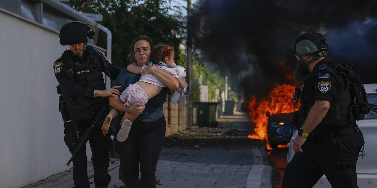 Agenti di polizia aiutano a far evacuare una donna e una bambina da un edificio colpito da un razzo lanciato da Hamas ad Ashkelon, nel sud di Israele, sabato 7 ottobre
