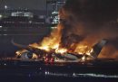 Un'aereo della compagnia giapponese Japan Airlines che brucia dopo essere atterrato all’aeroporto di Haneda, uno dei principali scali di Tokyo, ed essersi scontrato con un aereo della Guardia Costiera giapponese (Kyodo News via AP)