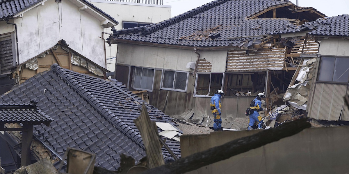 Due soccorritori cercano delle persone fra le case distrutte nella città di Wajima, nella provincia di Ishikawa (Kyodo News via AP)