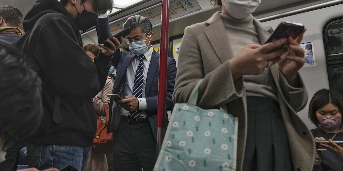 passeggeri seduti e in piedi in un vagone della metropolitana a Hong Kong tengono lo sguardo fisso sui loro smartphone
