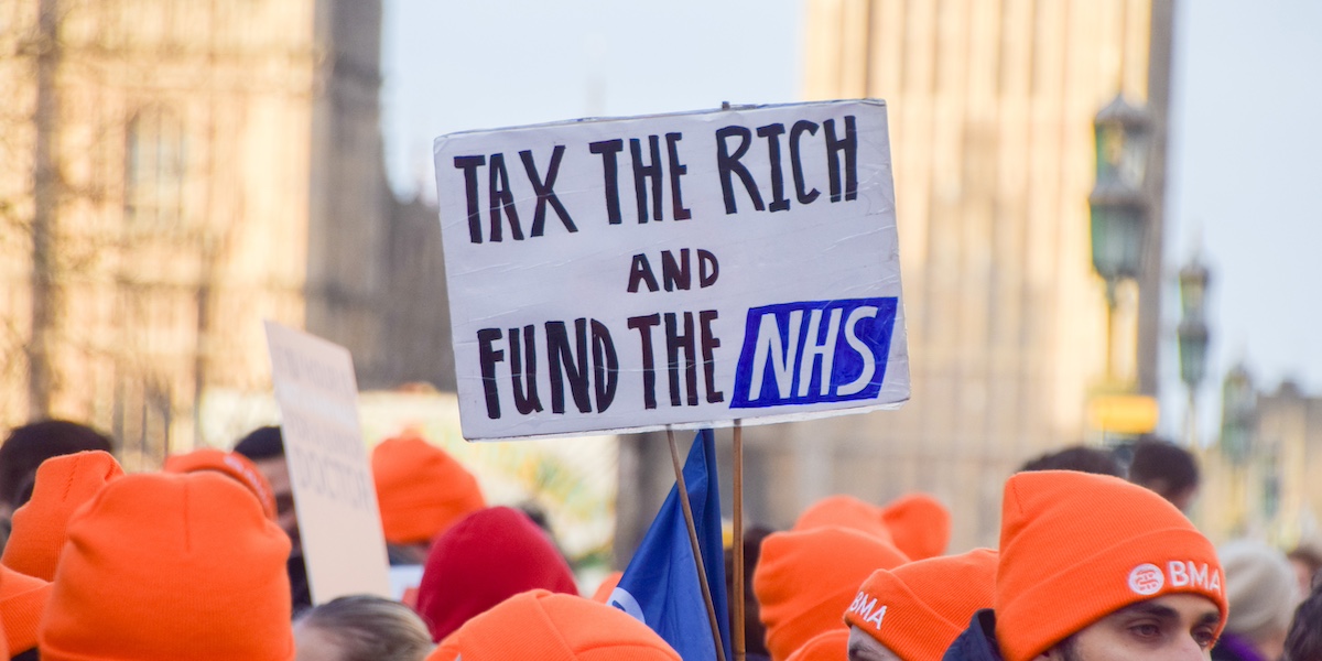 Un cartello con scritto "tassate i ricchi, finanziate il servizio sanitario nazionale" durante una manifestazione dei medici il 3 gennaio 2024 a Londra (Vuk Valcic / SOPA Images via ZUMA Press Wire / ANSA)