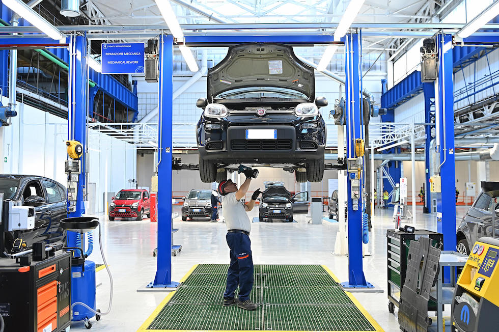 Un operaio al lavoro su un'auto nello stabilimento Stellantis a Mirafiori