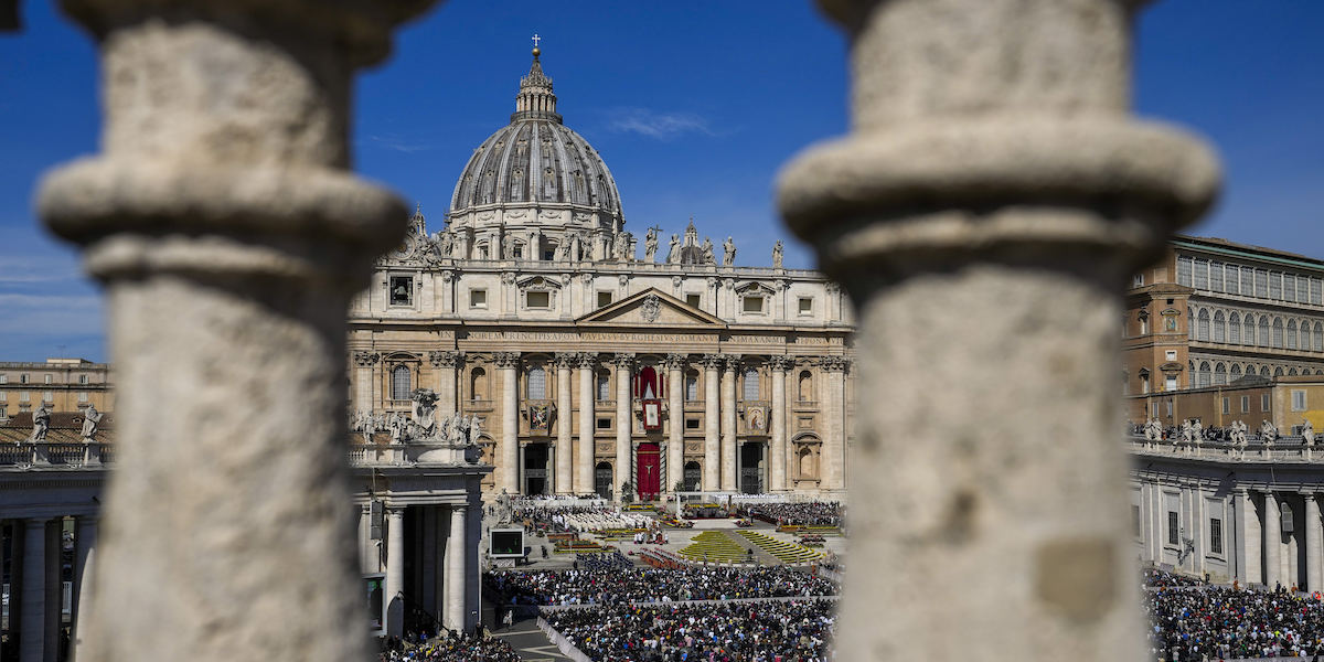 Foto della cupola di San Pietro in lontananza con una folla davanti