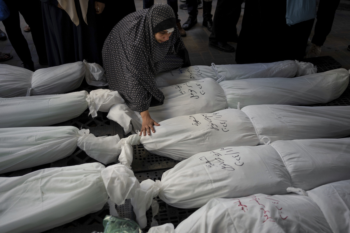 Una donna palestinese con i cadaveri di alcuni parenti uccisi da un bombardamento israeliano a gennaio 2024